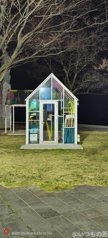 nubia Z70 Ultra カメラ 芝生のうえに立っているガラス張りの小屋を暗所撮影した写真